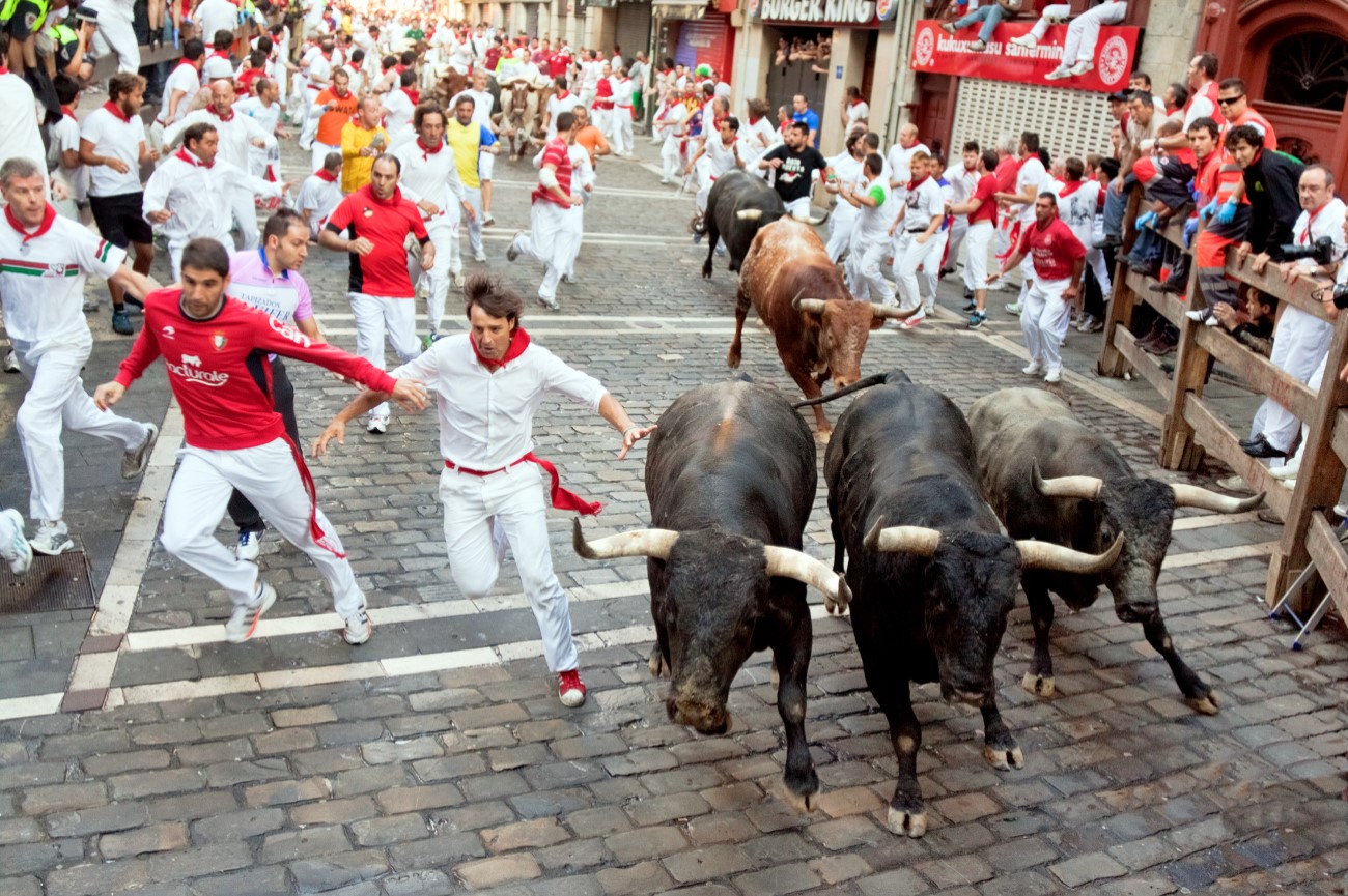 Men run from bulls in street Estafeta during San Fermin festival in Pamplona, Spain